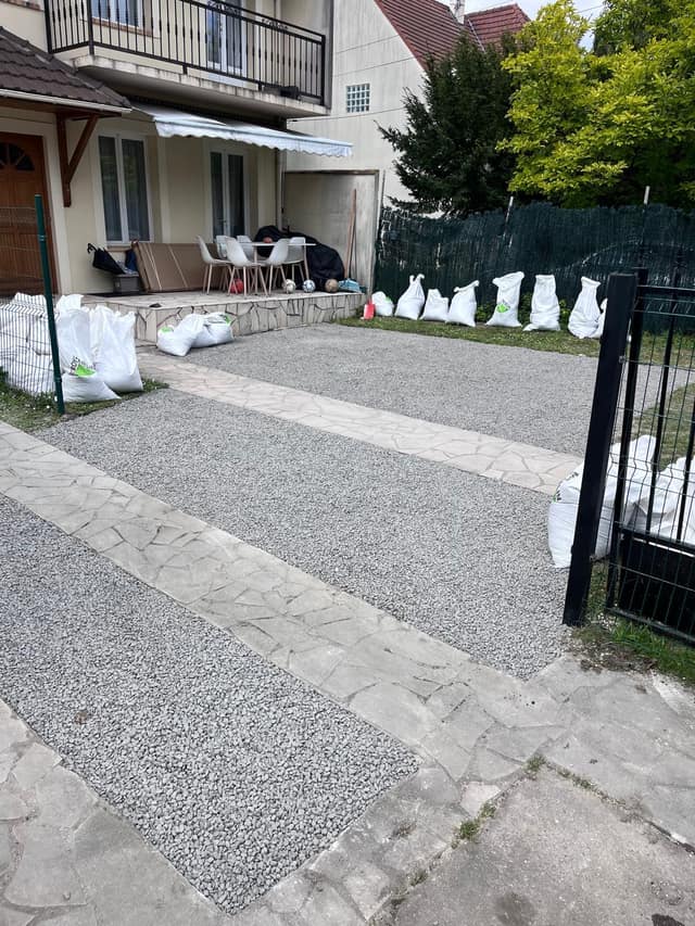 Cour terminée en gravillon gris avec bandes de dallage en pierre