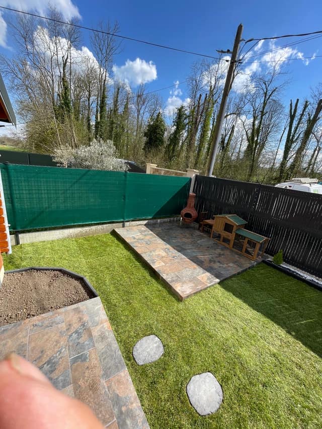 Terrasse en dallage pierre naturelle bordée de gazon et de pas japonais