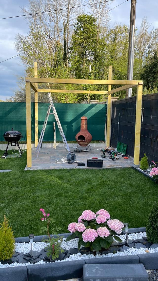 Montage de la structure en bois d'une pergola sur terrasse dallée