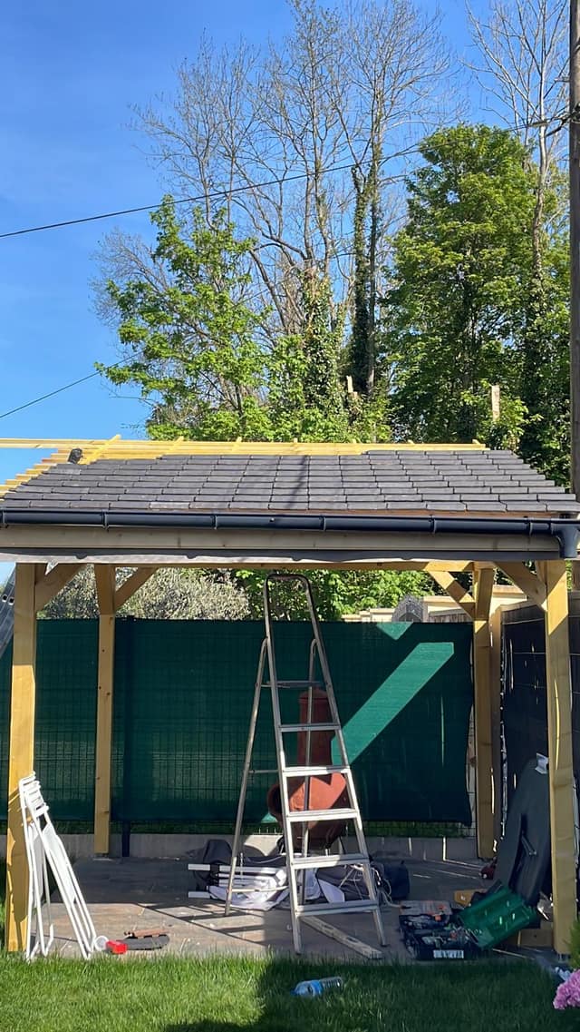 Pergola en bois avec charpente et couverture en tuiles plates en cours de pose