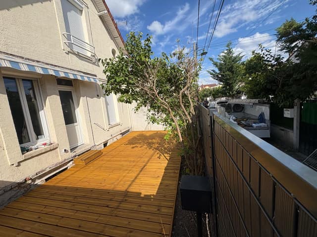 Terrasse en bois créée le long d'une maison avec clôture occultante
