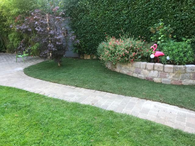 Jardin paysager avec muret en pierre, massif fleuri, érable pourpre et allée pavée
