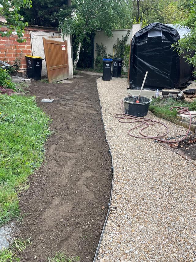 Allée gravillonnée avec bordure séparant une bande de terre dans un jardin
