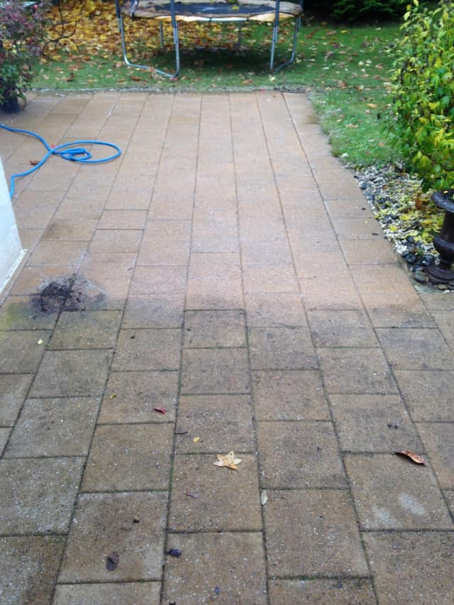 Nettoyage d'une terrasse en dalles béton : partie propre et partie encore encrassée de mousse